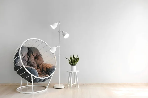 Comfortable armchair, lamp and table near light wall — Stock Photo, Image