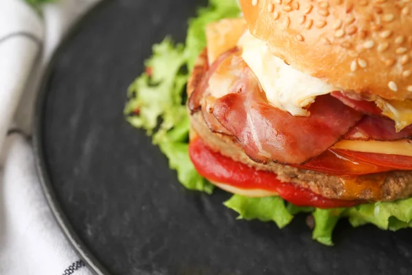 Tasty burger with bacon on plate, closeup