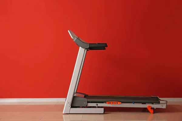 Modern treadmill near color wall — Stock Photo, Image