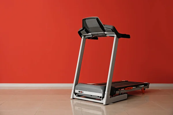 Modern treadmill near color wall — Stock Photo, Image