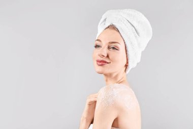 Gri arka plana vücut masajı yapan genç bir kadın.