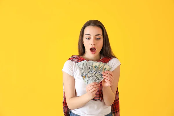 Giovane donna sorpresa con banconote in dollari su sfondo a colori — Foto Stock