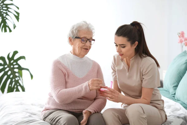 Caregiver giving medicine to senior woman in nursing home — Stock Photo, Image