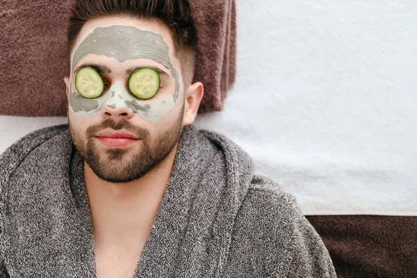 Jeune homme avec masque d'argile sur le visage dans un salon de beauté — Photo