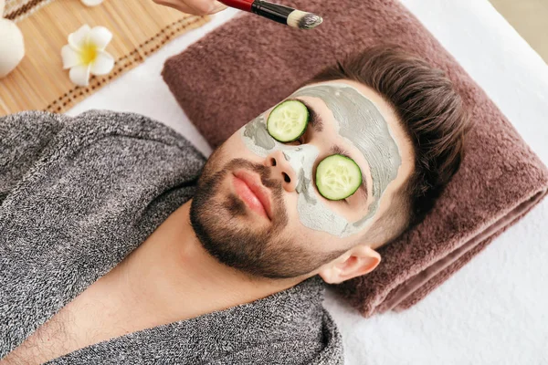 Jeune homme avec masque d'argile sur le visage dans un salon de beauté — Photo