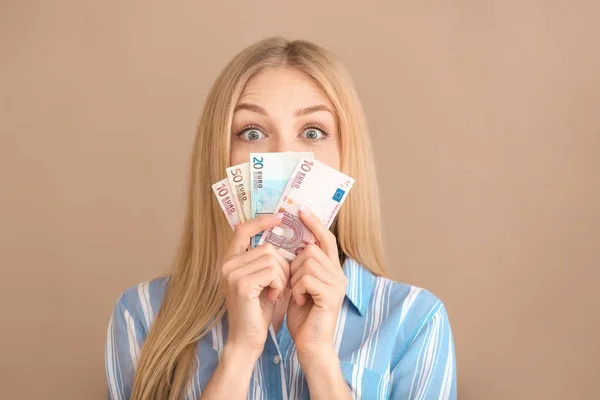 Mujer joven sorprendida con dinero en el fondo de color — Foto de Stock