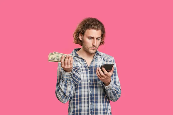 Confused man with money and calculator on color background