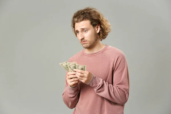 Hombre trastornado con dinero sobre fondo gris — Foto de Stock