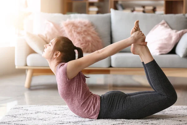 Ung kvinna som utövar yoga hemma — Stockfoto