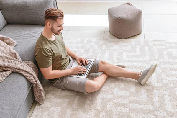 Beau homme avec ordinateur portable reposant à la maison — Photo