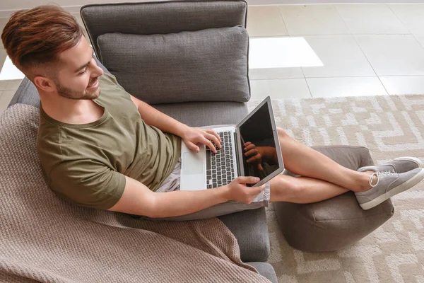 Красивий чоловік з ноутбуком відпочиває вдома — стокове фото