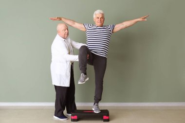 Klinikte olgun adam ile çalışan kıdemli fizyoterapist