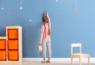 Odada renkli duvara sevimli küçük kız boyama