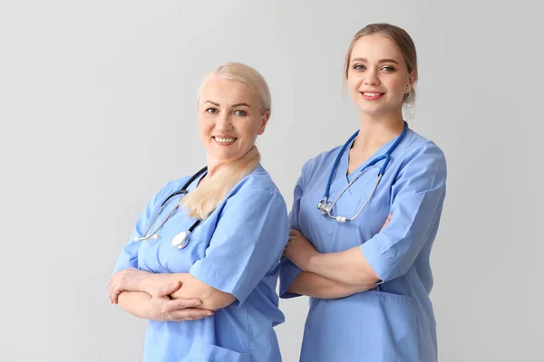 Молоді та зрілі медичні помічники на сірому фоні — стокове фото