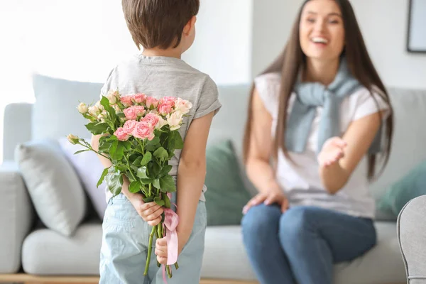 Little boy hiding bouquet of flowers for his mother behind back at home — Stock Photo, Image