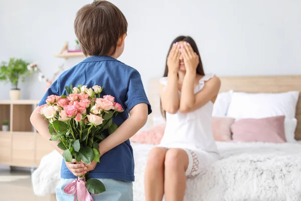 Kleine jongen verbergen boeket van bloemen voor zijn moeder achter terug thuis — Stockfoto