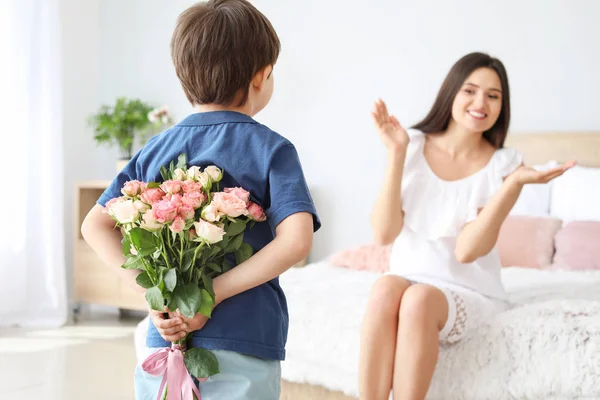 Little boy hiding bouquet of flowers for his mother behind back at home — Stock Photo, Image