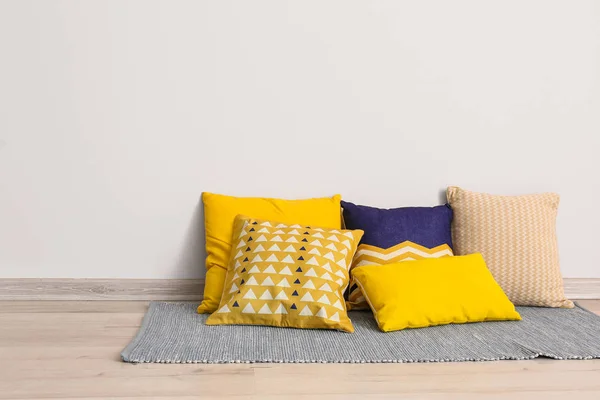 Soft pillows on floor near light wall — Stock Photo, Image