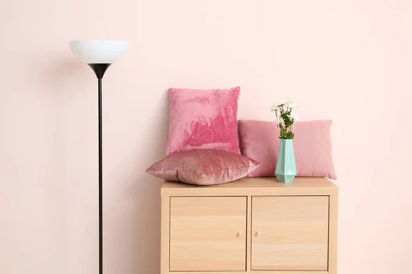 Cabinet with soft pillows and lamp near color wall — Stock Photo, Image