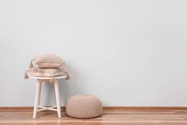 Taburete con almohadas suaves y puf cerca de la pared de luz — Foto de Stock