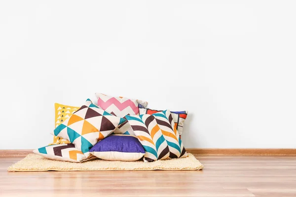 Soft pillows on floor near light wall — Stock Photo, Image