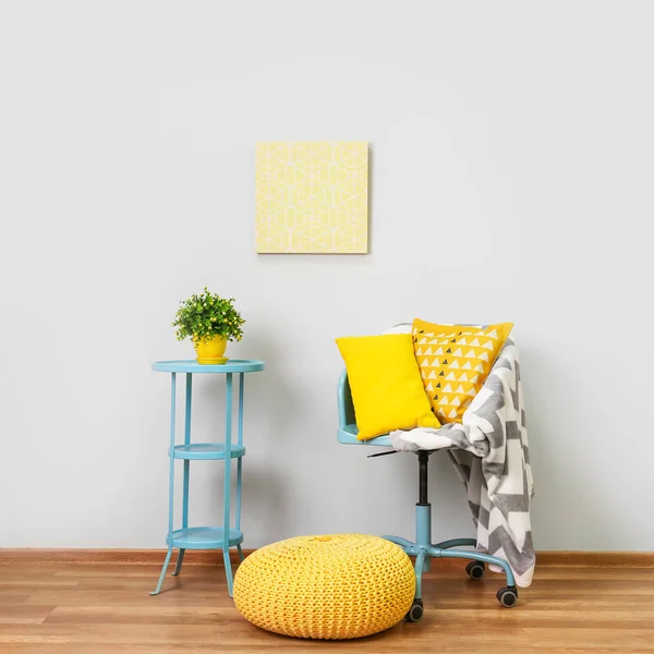 Chair with pillows, table and pouf near light wall — Stock Photo, Image