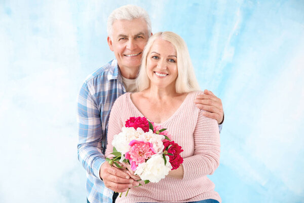Portrait of happy mature couple with flowers on color background