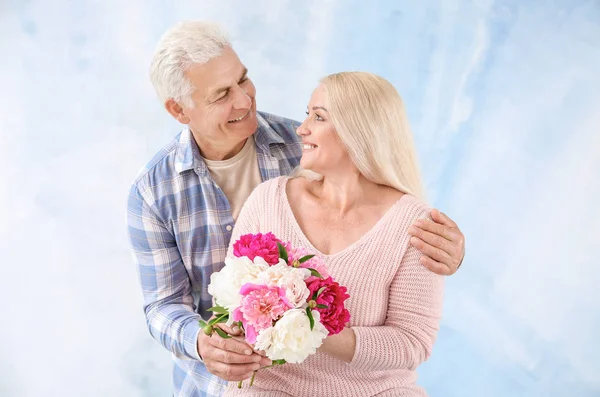 Retrato de feliz pareja madura con flores sobre fondo de color —  Fotos de Stock