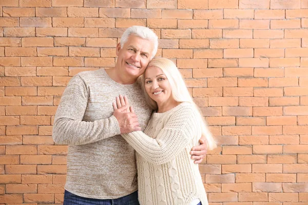 Portrait of happy mature couple against brick wall — Stock Photo, Image
