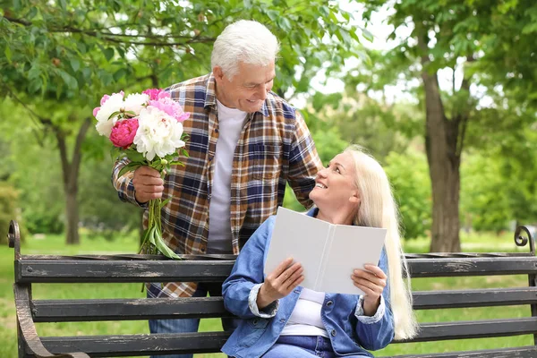 Mujer madura recibiendo flores de su marido en el parque —  Fotos de Stock