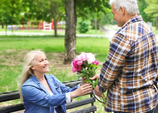 Parkta kocasından çiçek alan olgun kadın — Stok fotoğraf
