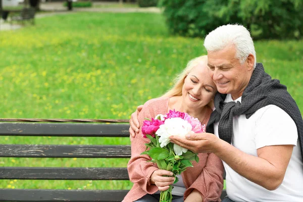 Retrato de pareja madura feliz con flores en el parque —  Fotos de Stock