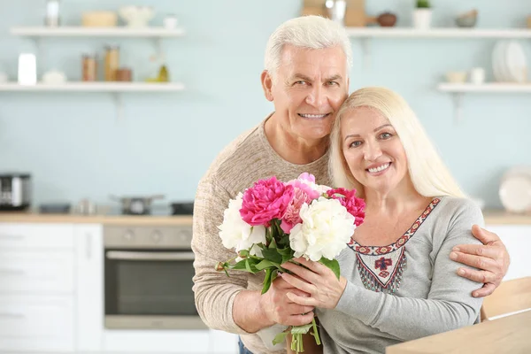 Portrait of happy mature couple with flowers in kitchen — Stock Photo, Image