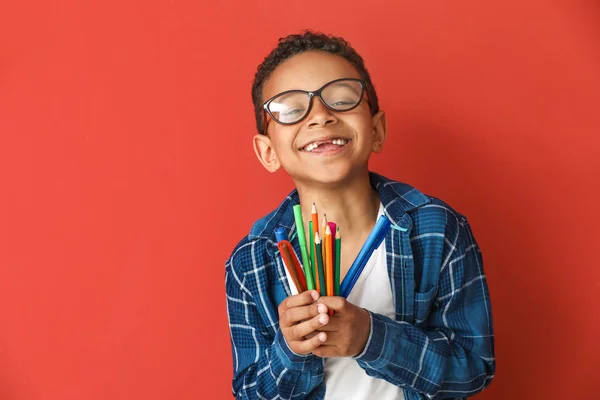 Cute African-American boy with pencils and markers on color background — Stock Photo, Image