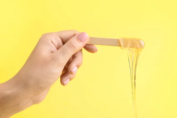 Female hand with sugaring paste on stick against color background — Stock Photo, Image