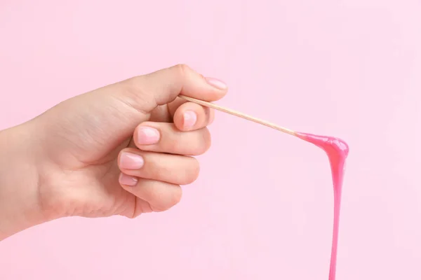 Female hand with sugaring paste on stick against color background — Stock Photo, Image