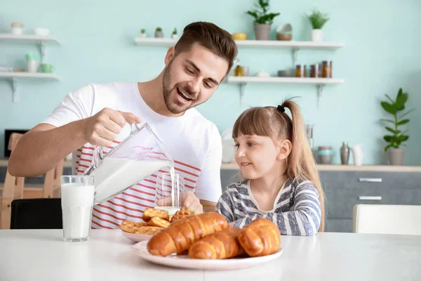 Young father with little daughter drinking tasty milk in kitchen at home — Stock Photo, Image