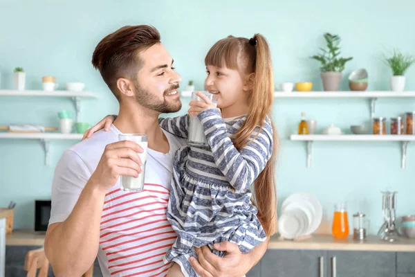 El padre joven con su hija bebiendo la leche sabrosa en la cocina en casa —  Fotos de Stock
