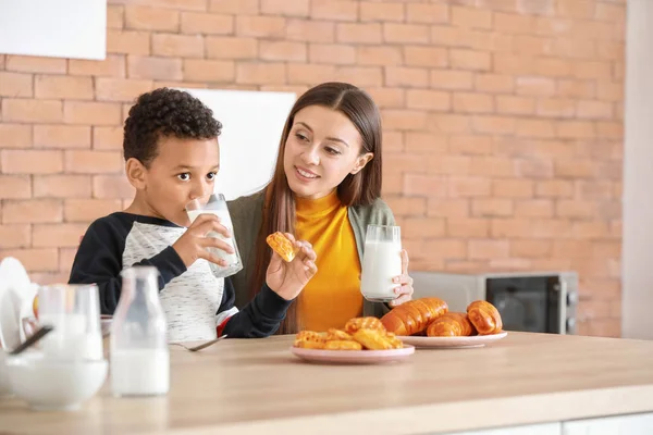 年轻母亲和养子在家里厨房里喝美味的牛奶 — 图库照片