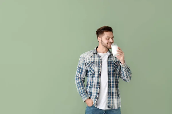 Handsome man drinking tasty milk on color background — Stock Photo, Image