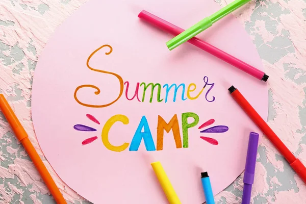 Sheet of paper with text SUMMER CAMP and felt-tip pens on color background — Stock Photo, Image