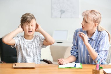 Kadın psikolog ofiste yaramaz küçük çocuk ile çalışıyor