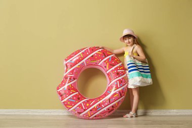 Renkli duvar yakın şişme yüzük ve plaj çantası ile sevimli küçük kız