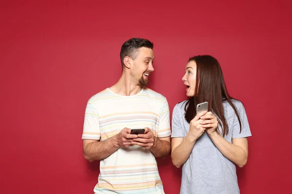 Young couple with mobile phones on color background — Stock Photo, Image