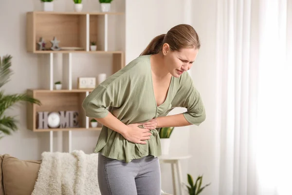 Ung kvinna som lider av buksmärta hemma — Stockfoto