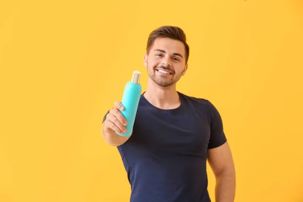Hombre guapo con botella de champú sobre fondo de color — Foto de Stock