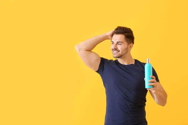 Hombre guapo con botella de champú sobre fondo de color — Foto de Stock