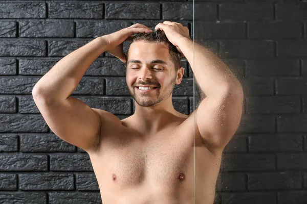 Yakışıklı adam koyu arka plan üzerinde saç yıkama