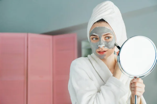 Jonge vrouw het toepassen van klei masker thuis — Stockfoto