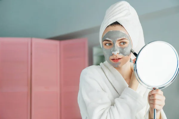 Wanita muda menerapkan masker tanah liat di rumah — Stok Foto